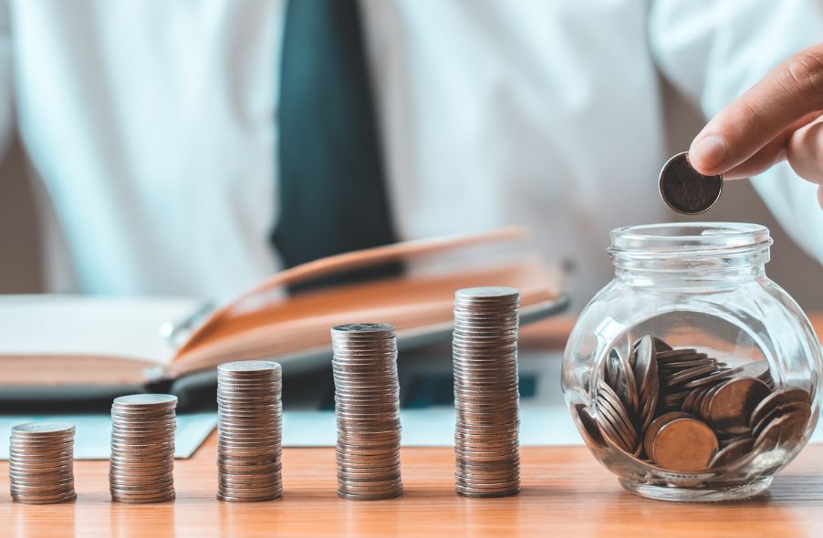 businessman stacking coins and putting in jar